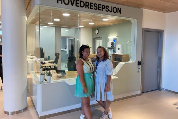 Et par kvinner poserer for et bilde foran en butikk