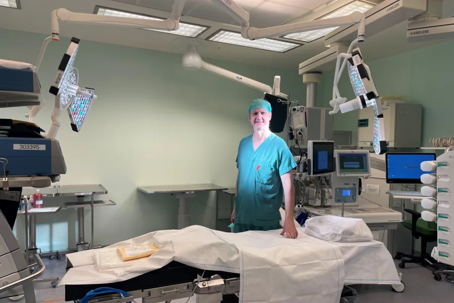 Knut Jørgen Labori i grønt operasjonsantrekk, på operasjonsstua bak sengen med lys