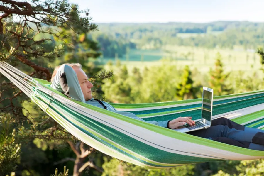 En person som ligger på en hengekøye med en bærbar datamaskin