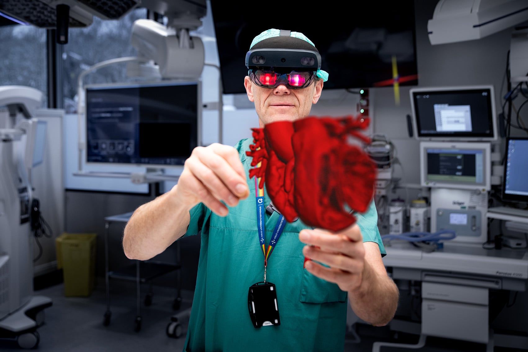 Henrik Brun står i grønt i en operasjonssal og har på seg 3D-briller som visualiserer et hjerte i 3D.