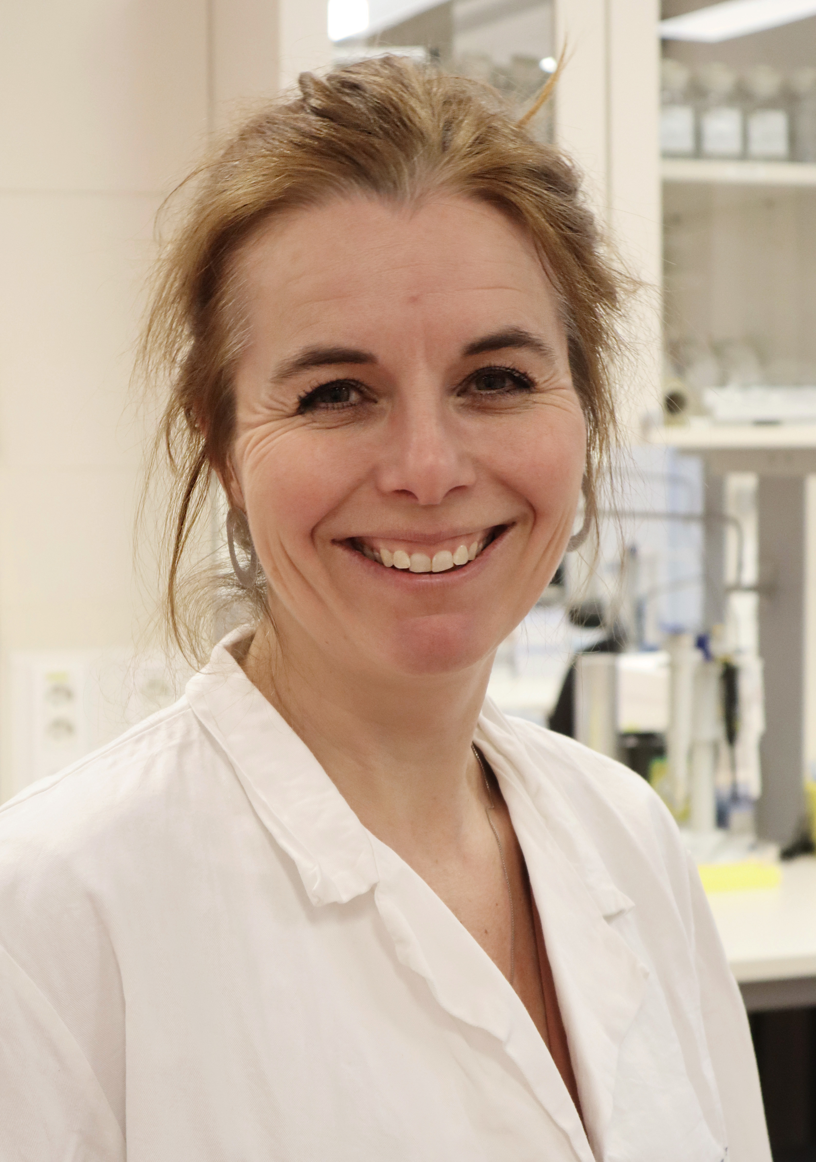 Anette Weyergang i hvit labfrakk smiler mot kameraet.