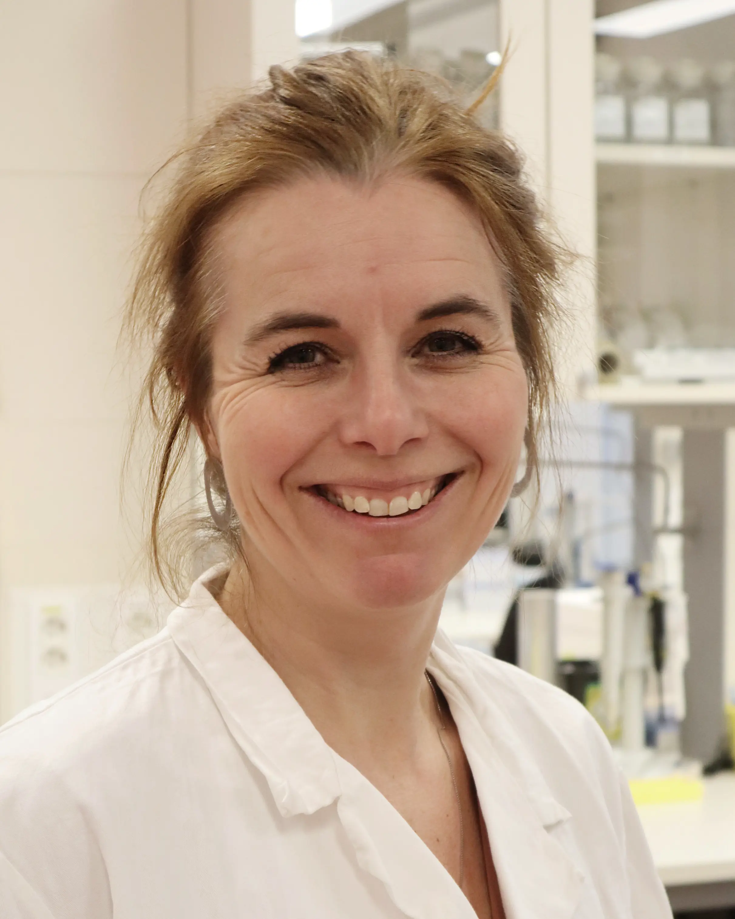 Anette Weyergang i hvit labfrakk smiler mot kameraet.