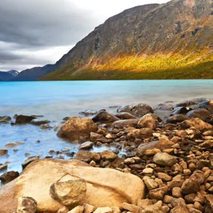En steinete strand med et fjell i bakgrunnen