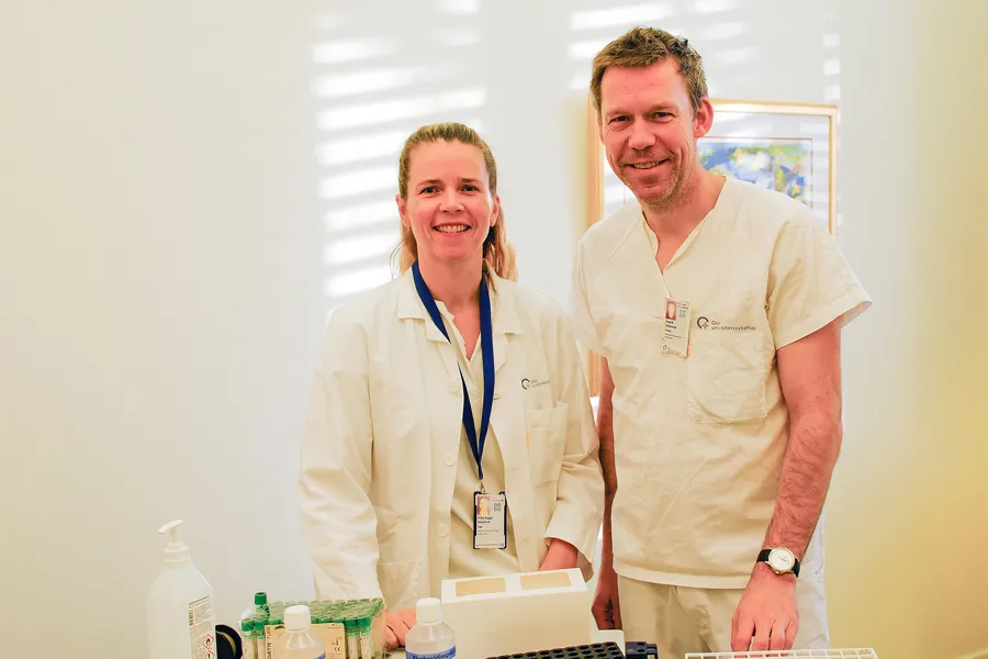 En mann og en kvinne i laboratoriefrakker står ved siden av en datamaskin