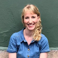 A person smiling in front of a green wall