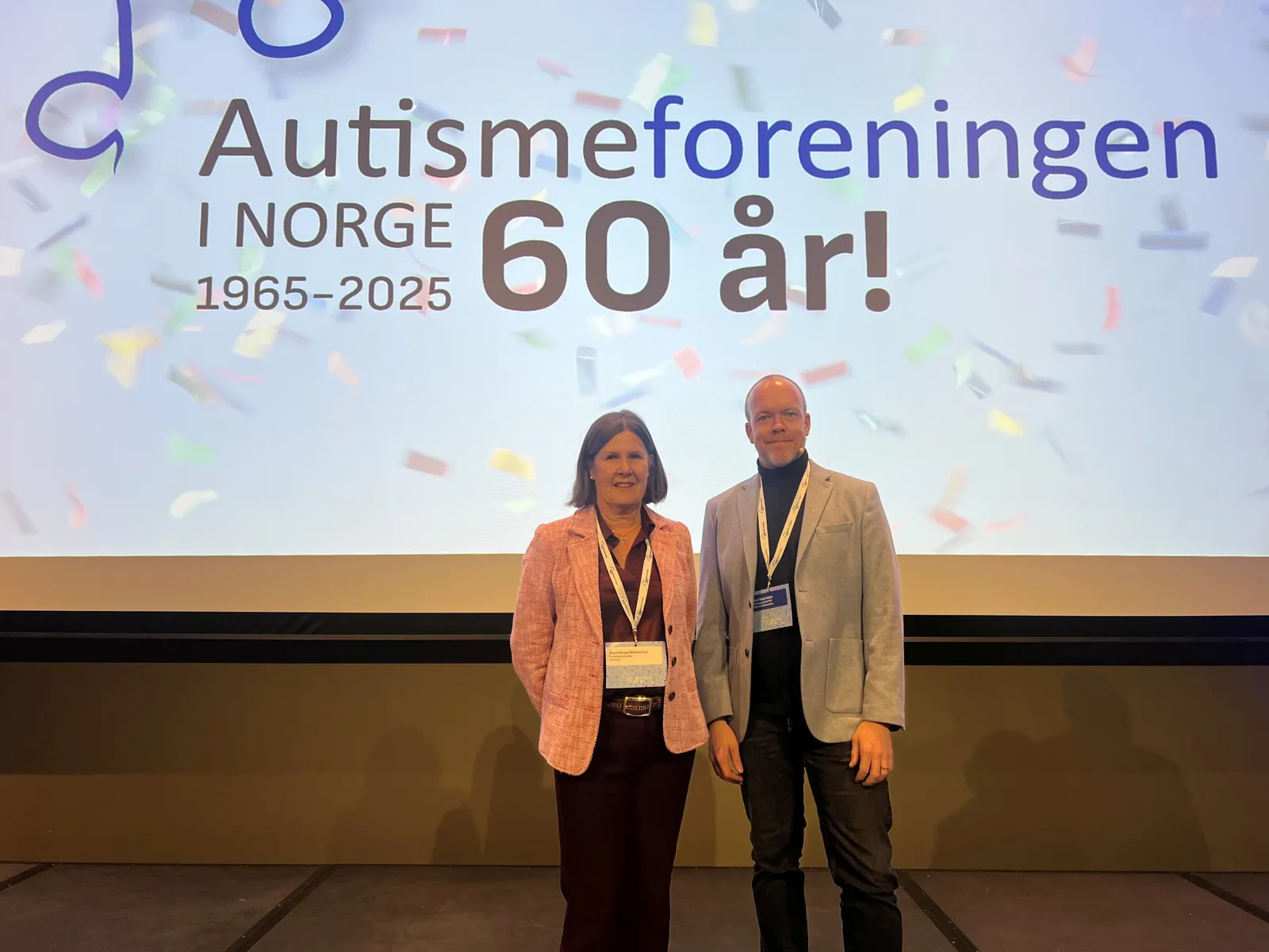 En mann og en kvinne står foran en stor skjerm