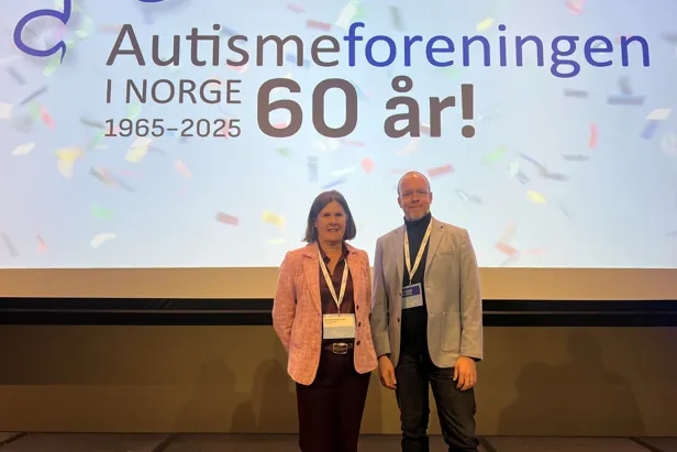 En mann og en kvinne står foran en stor skjerm
