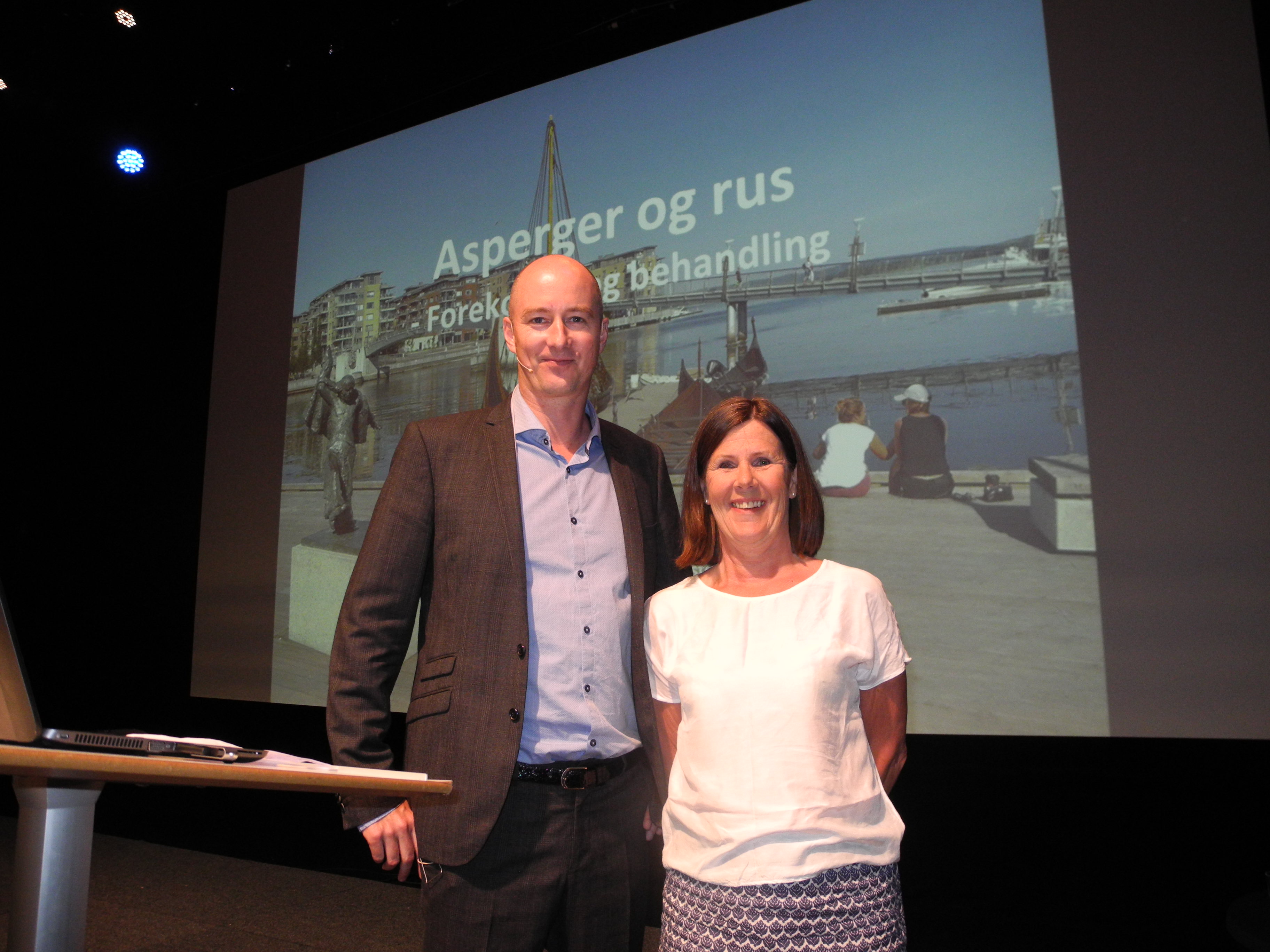 En mann og en kvinne står foran en stor skjerm