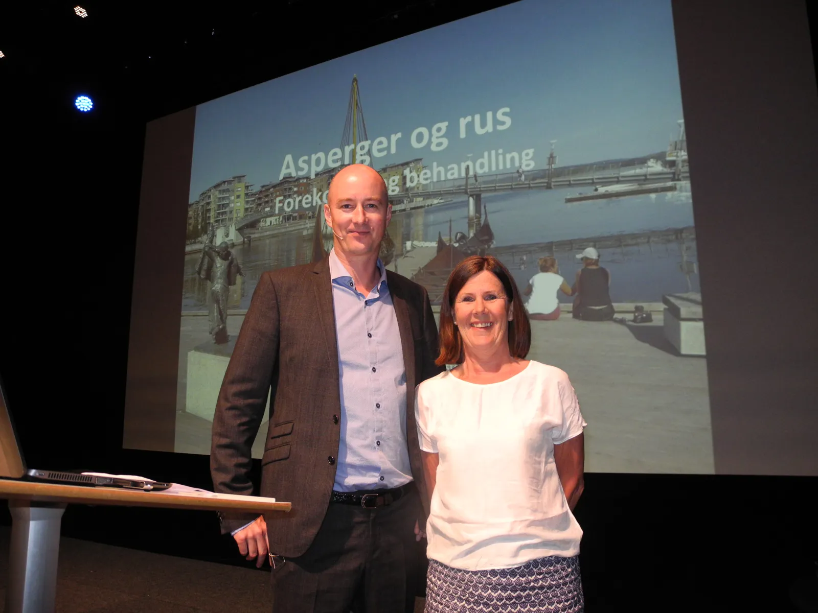 En mann og en kvinne står foran en stor skjerm