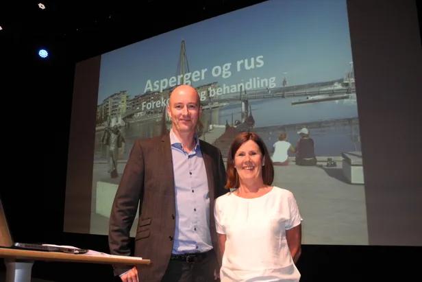 En mann og en kvinne står foran en stor skjerm