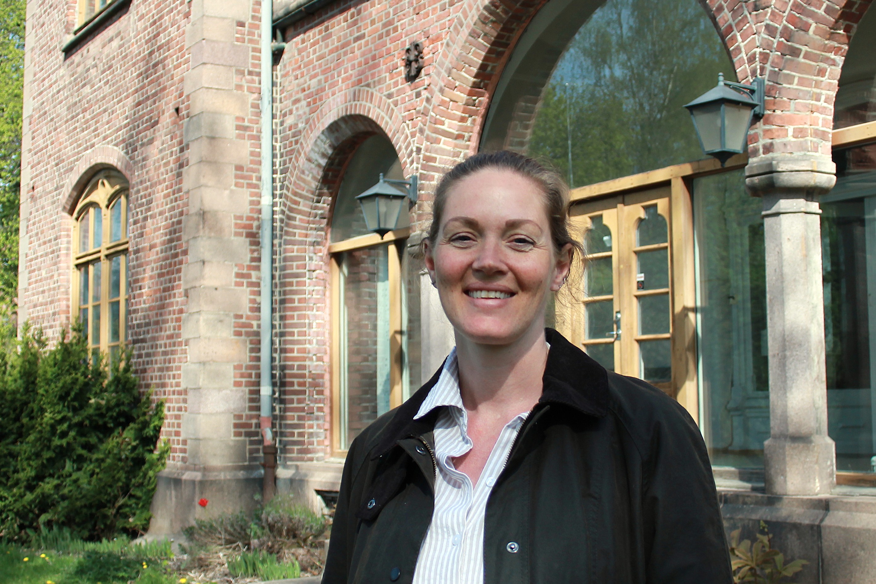 En kvinne som smiler foran en bygning