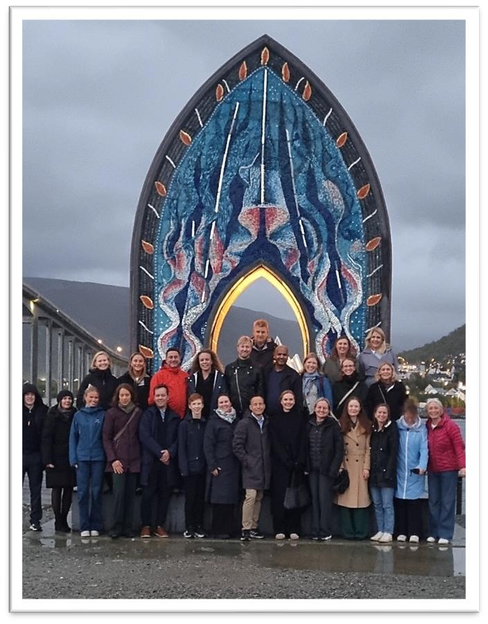 En gruppe mennesker poserer for et bilde foran en stor skulptur