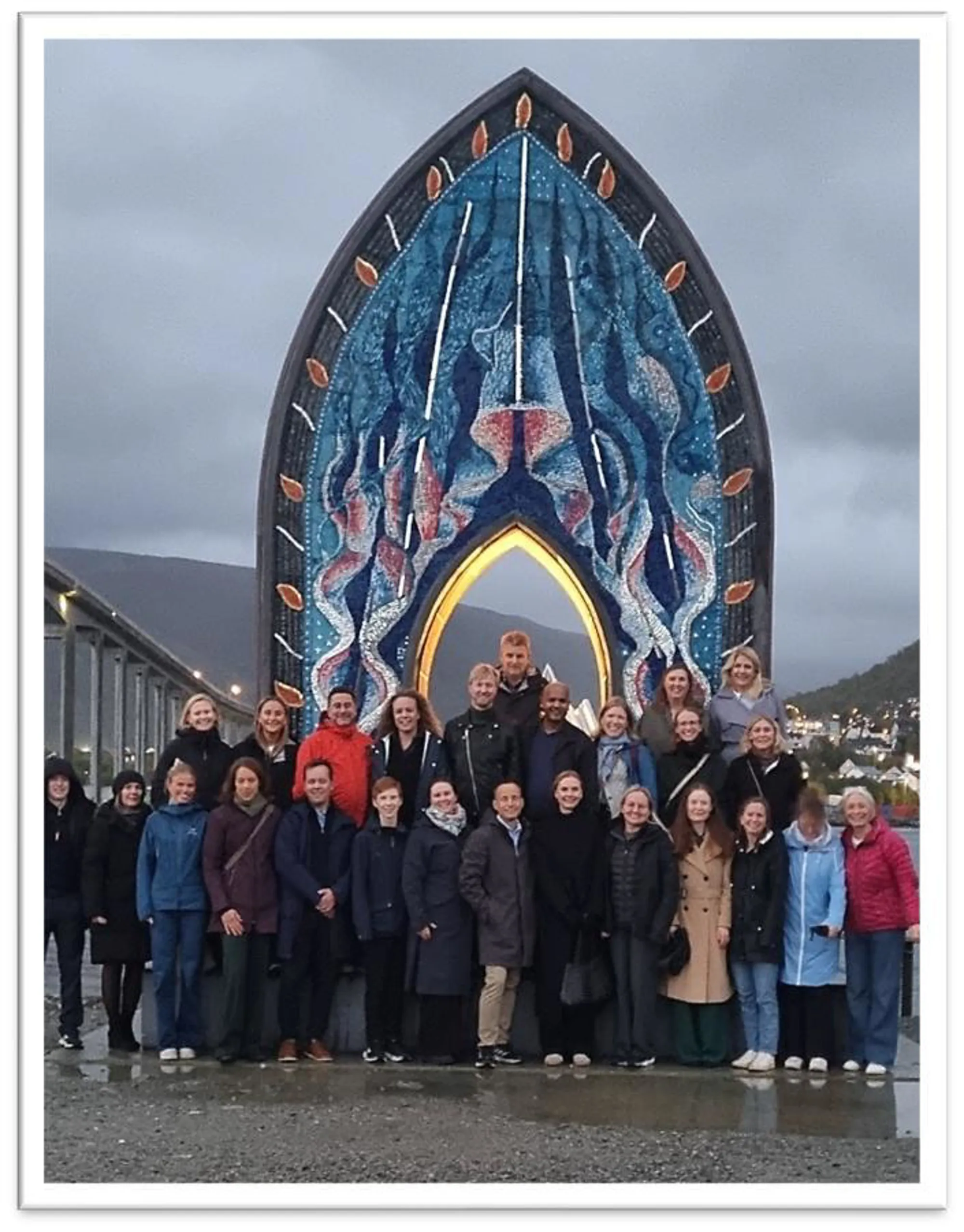En gruppe mennesker poserer for et bilde foran en stor skulptur