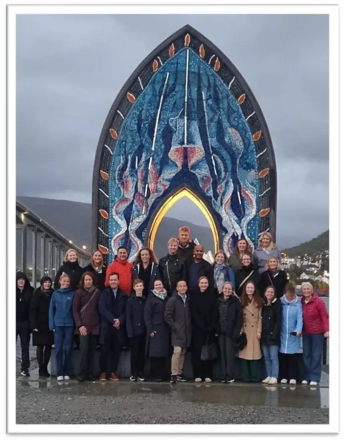 En gruppe mennesker poserer for et bilde foran en stor skulptur