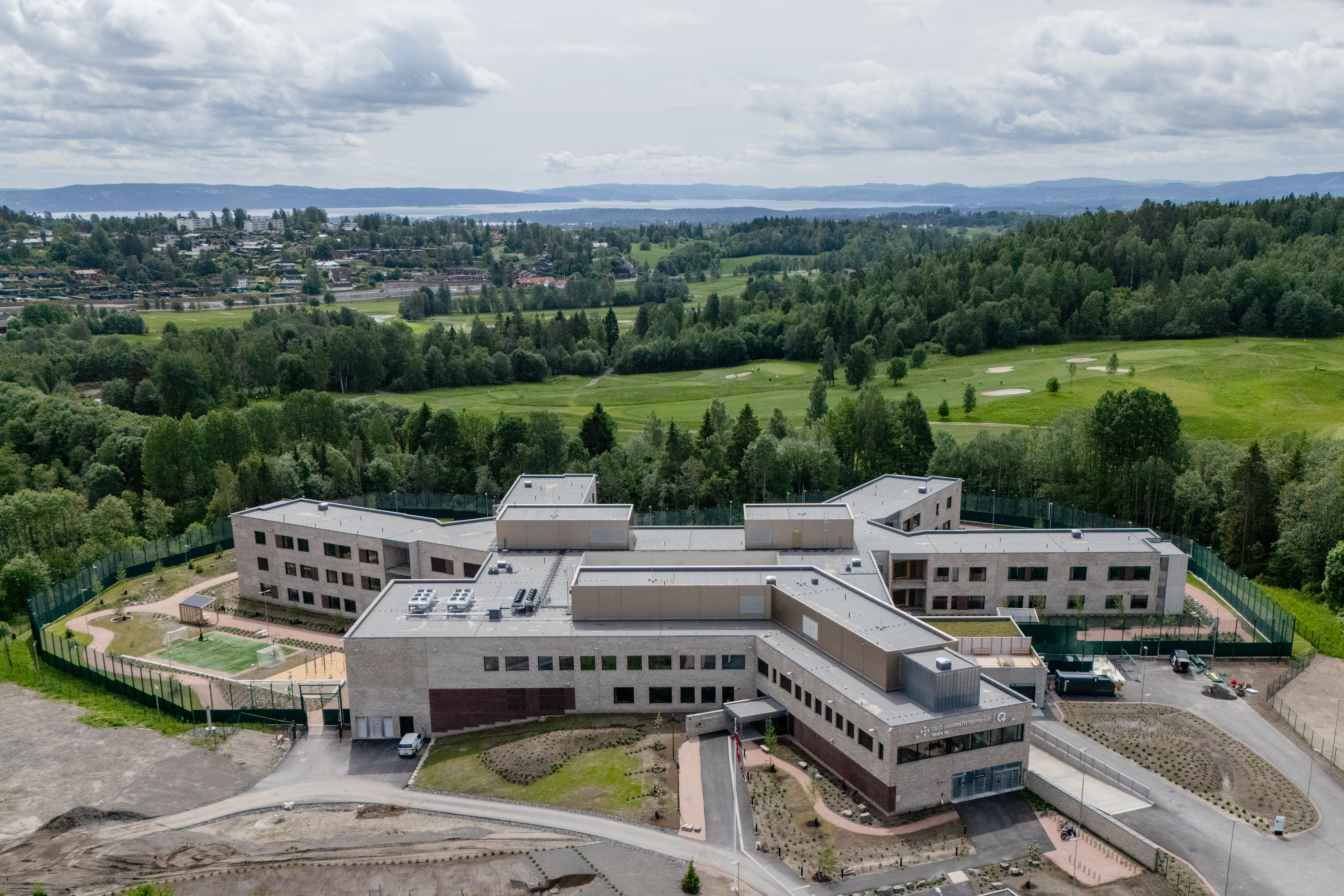 Oversiktsbilde av Nedre Ila sett ovenfra. Det viser ett bygg formet som en slags stjerne, omringet av skog og grønn park.