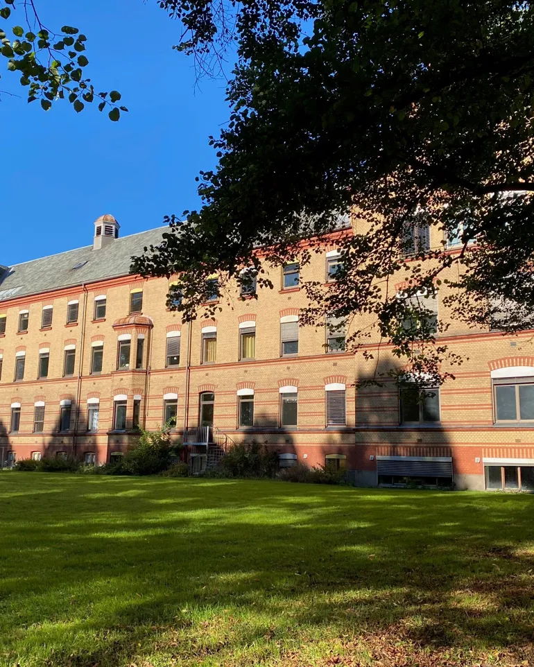 En stor murbygning med en plen foran