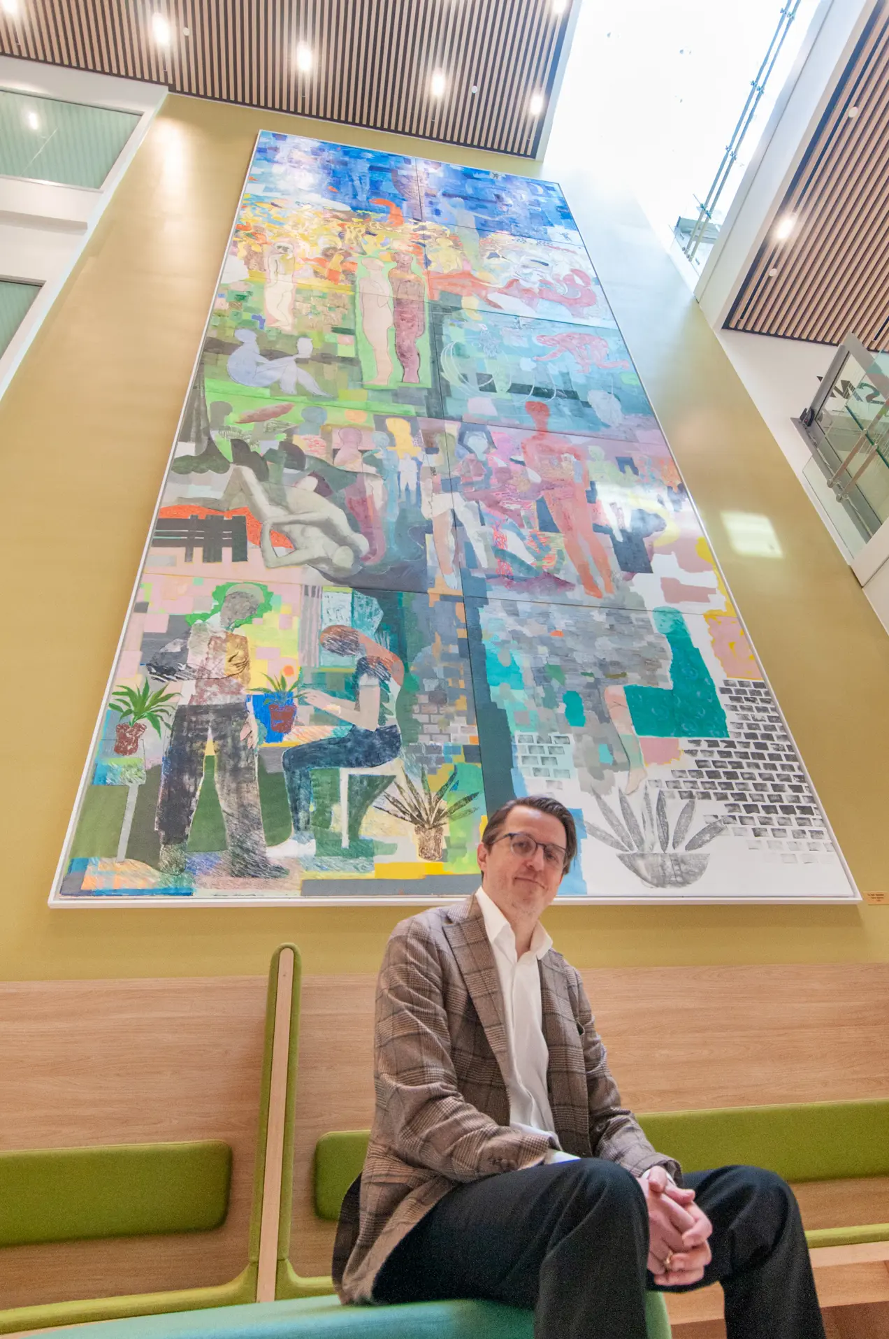 Bilde av Sverre Bjertnæs som sitter på en benk foran sitt store maleri