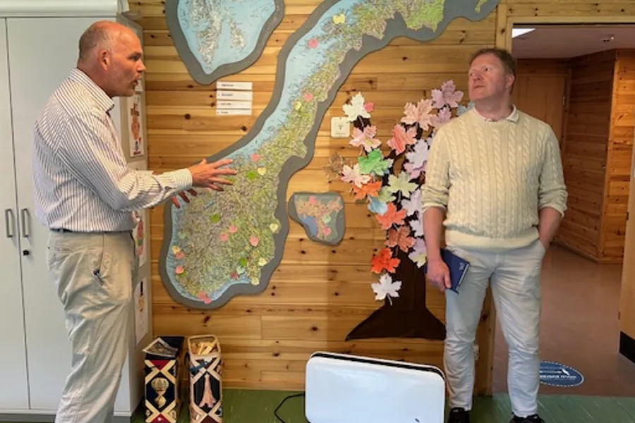 To menn foran et norgeskart som snakker sammen