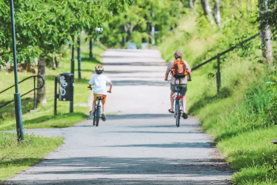 Et par personer som sykler nedover en sti i en park