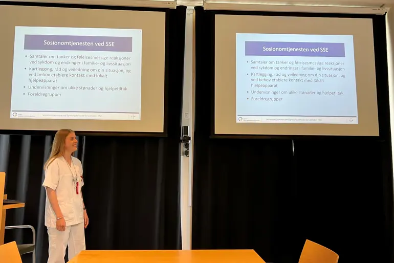 Ida Otterdal Ofrim, som står foran en presentasjon med undervisningsmateriell om sosionomtjenesten ved SSE