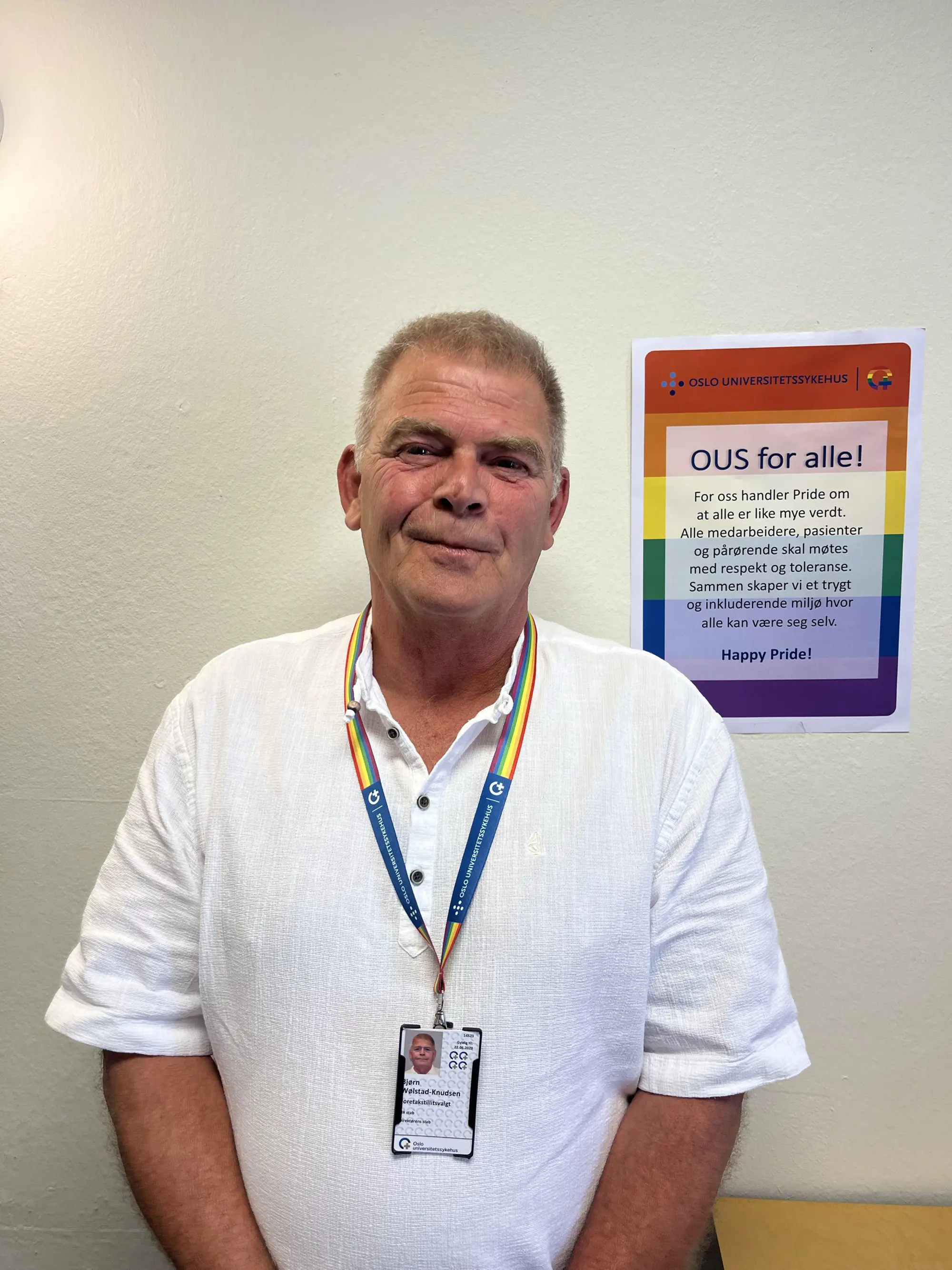 Bjørn Wølstad-Knudsen som smiler foran en Pride-plakat