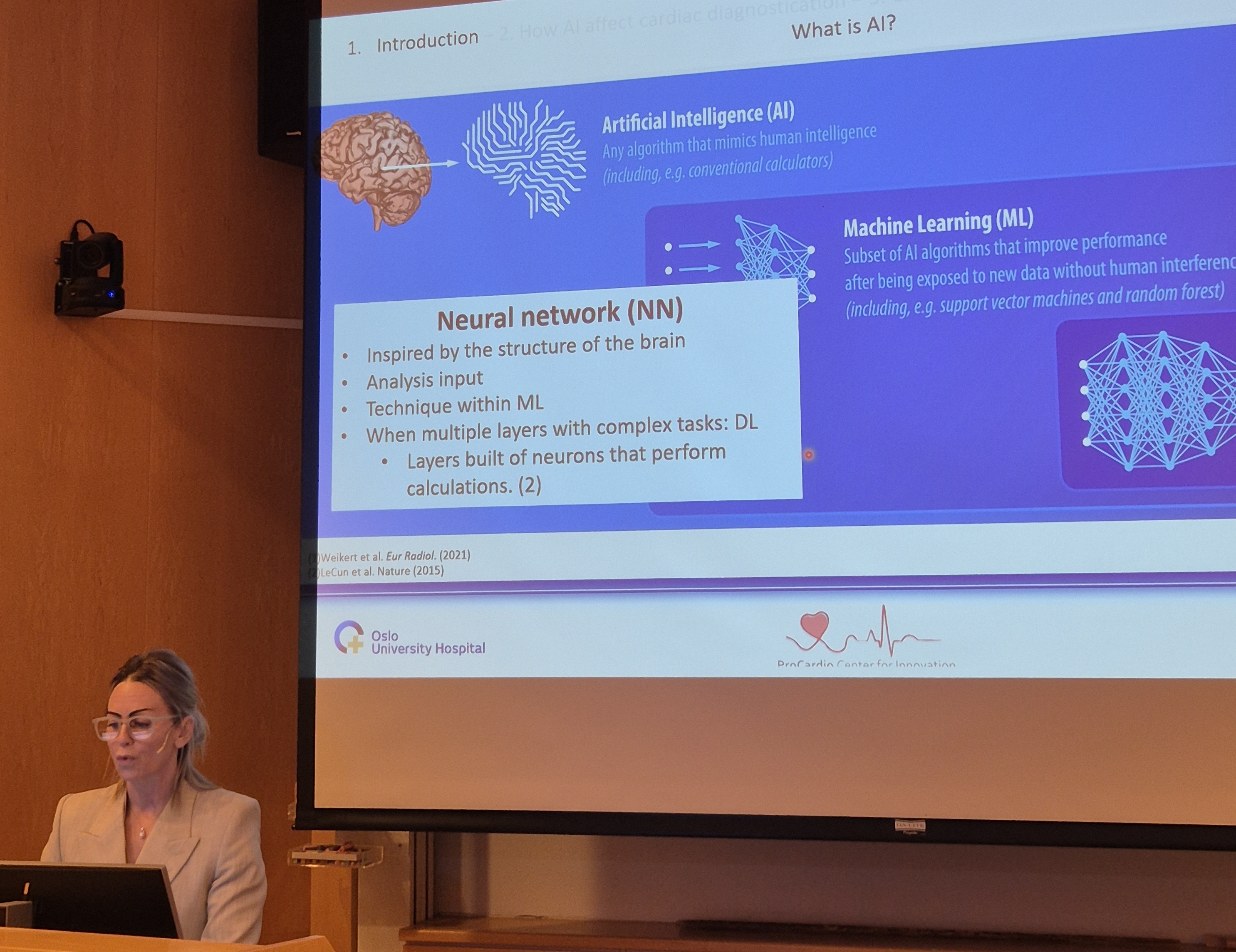 A person sitting at a desk in front of a large screen