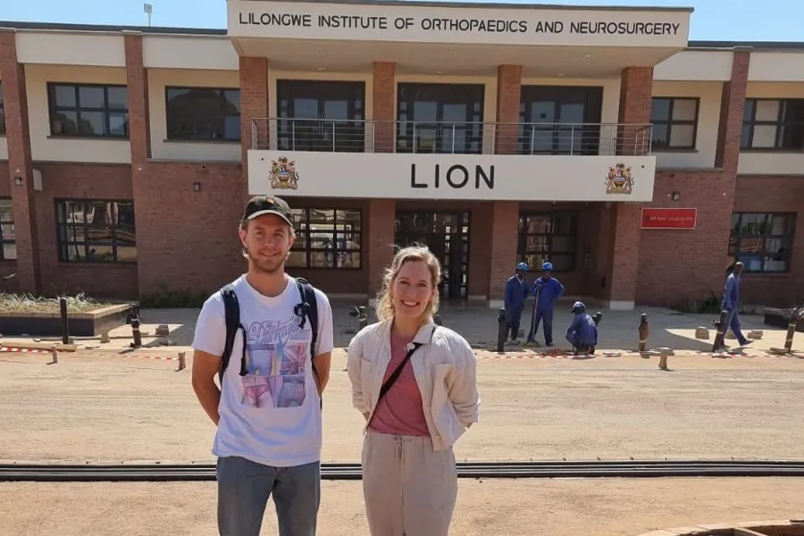 En mann og kvinne som poserer for et bilde foran en bygning