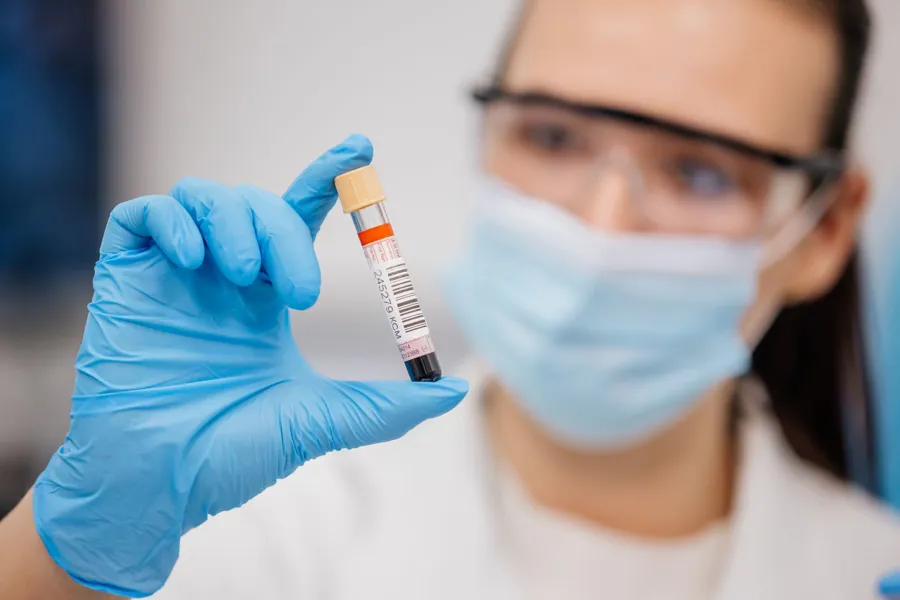 En person i en hvit laboratoriefrakk som holder en sprøyte