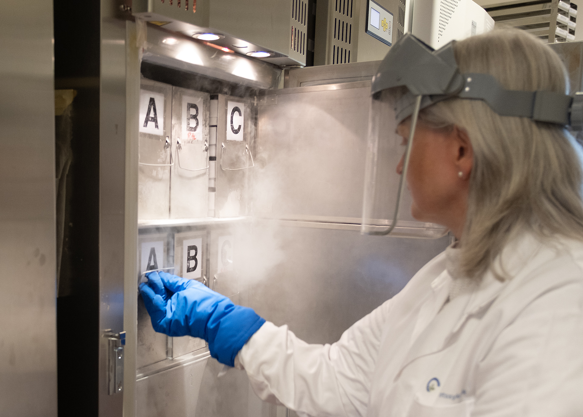 En person iført hvit laboratoriefrakk og hansker