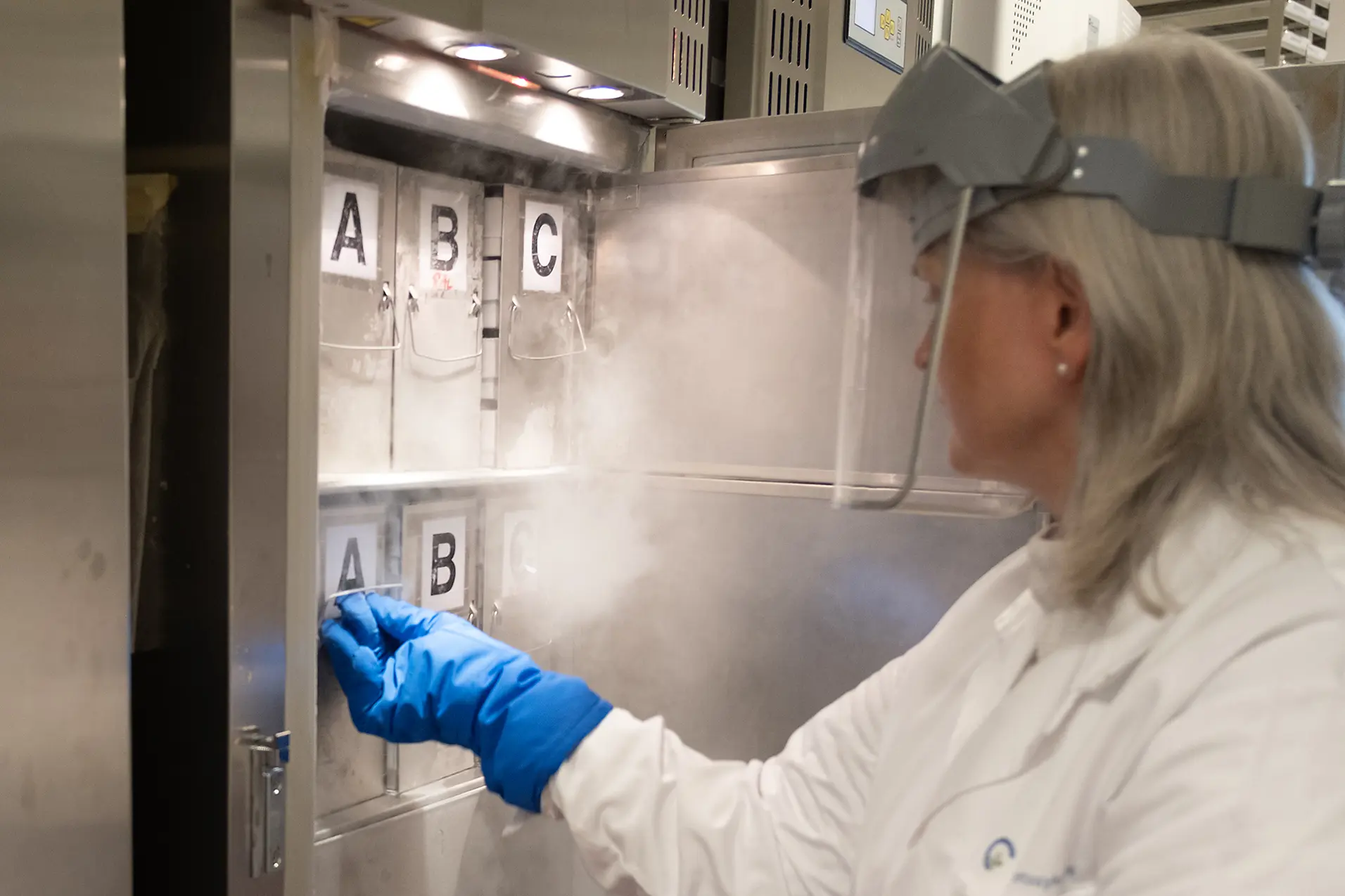 En person iført hvit laboratoriefrakk og hansker