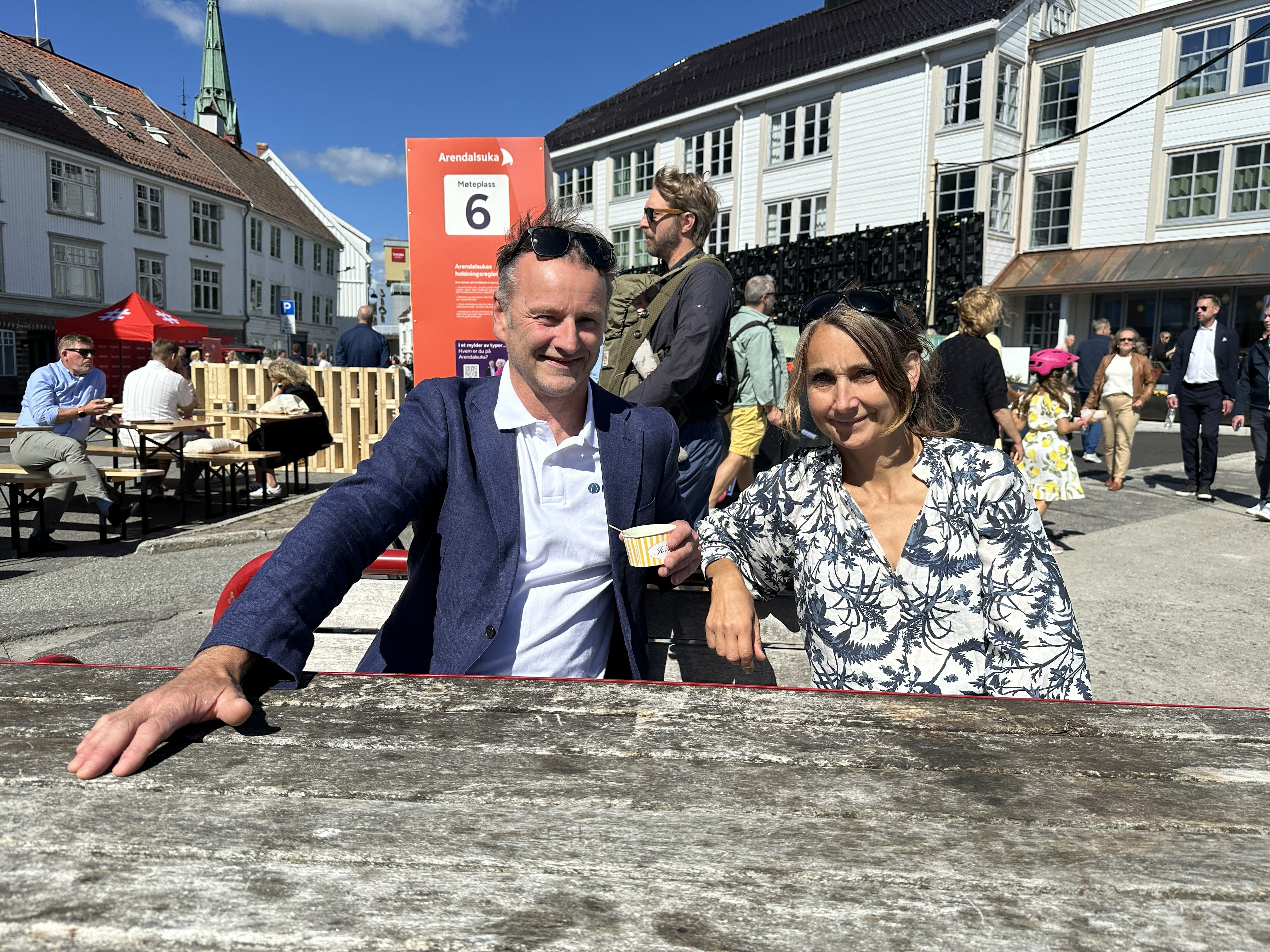 En mann og en kvinne som sitter på benk foran en folkemengde