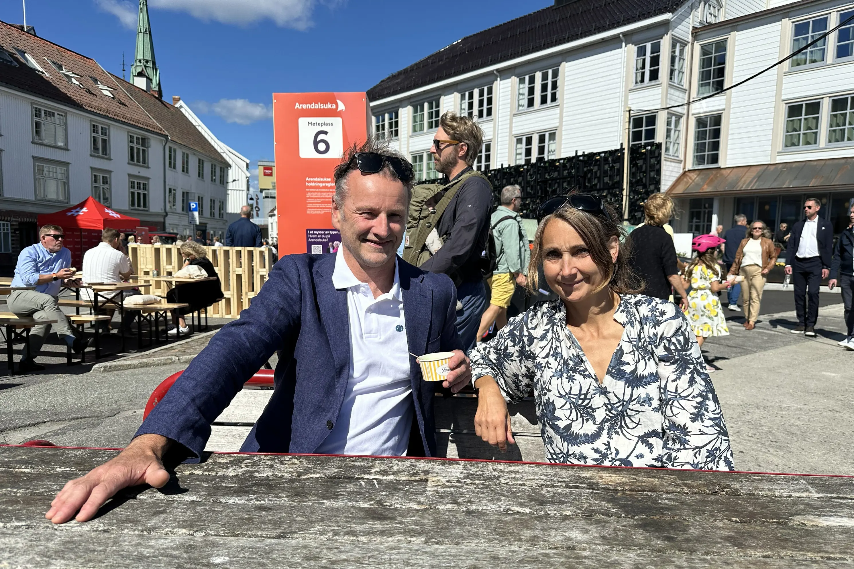 En mann og en kvinne som sitter på benk foran en folkemengde