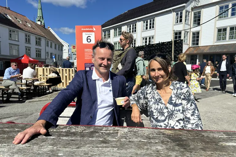 En mann og en kvinne som sitter på benk foran en folkemengde