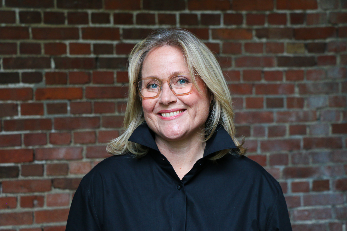 En mann som smiler foran en murvegg