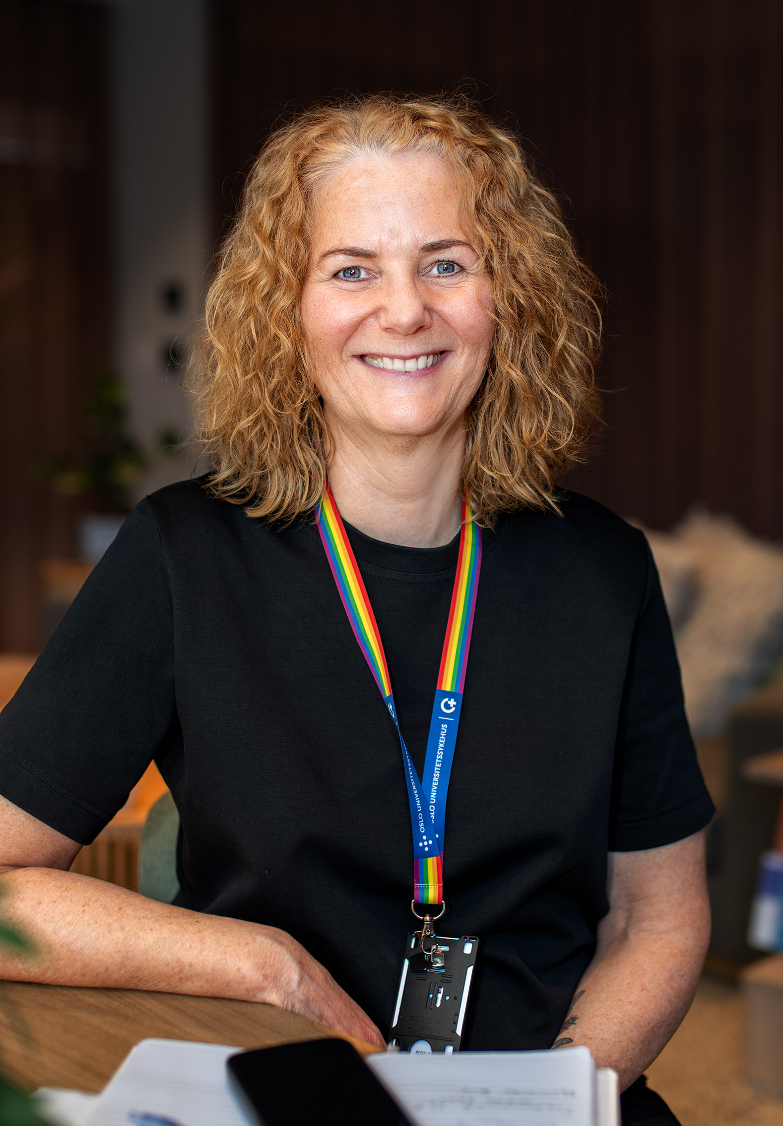 Trude Aamotsmo smiler mot kameraet. Hun har et OUS-nøkkelkort hengende rundt halsen.