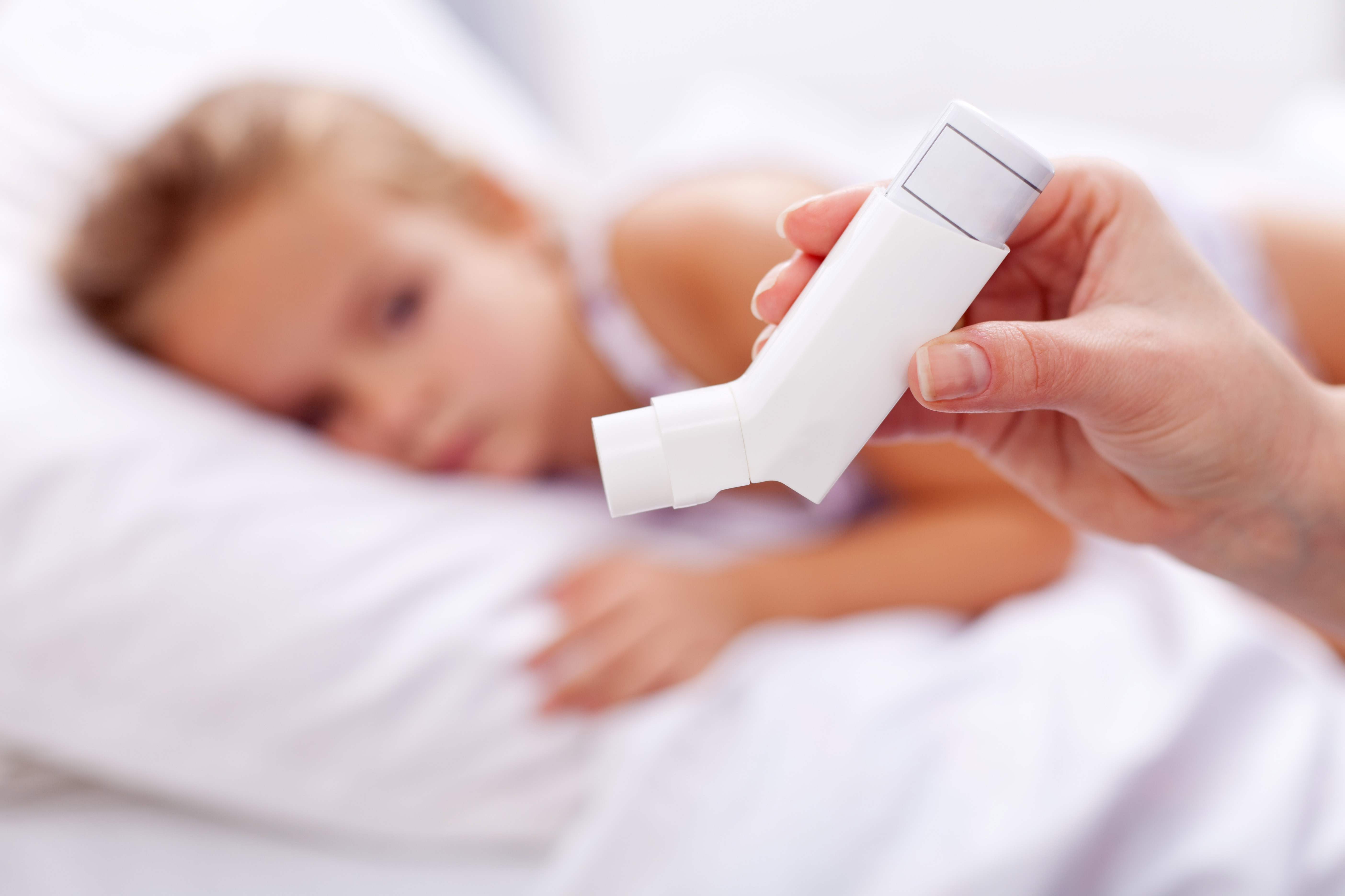 Barn med astma i seng med inhalator