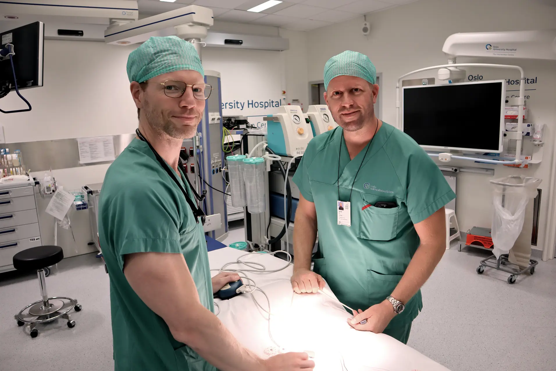 Et par personer i kirurgiske uniformer i et rom med datamaskiner
