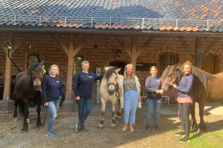 En gruppe mennesker som står ved siden av hester