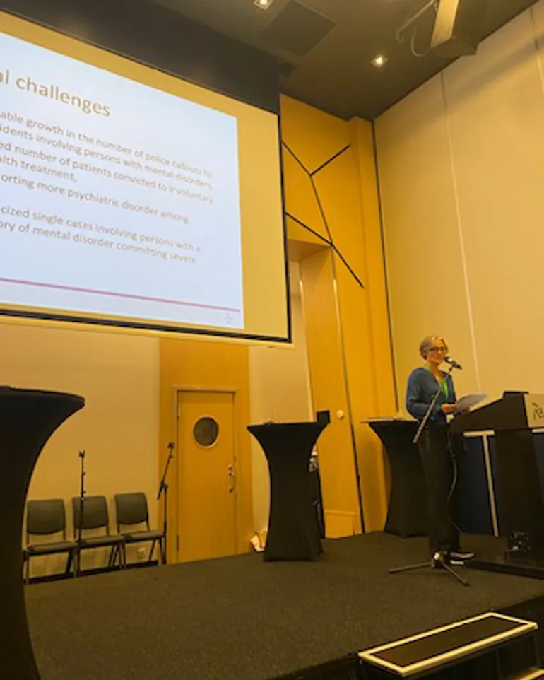 En person som står på et podium foran en projektorskjerm