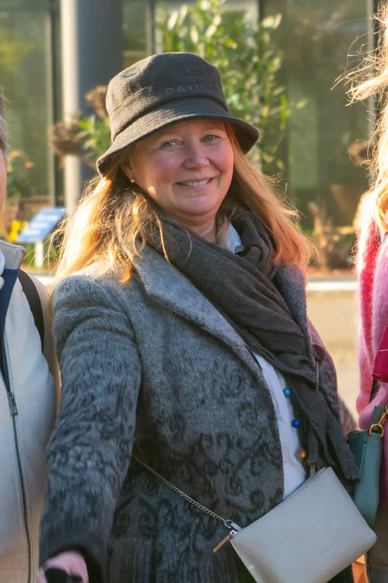Nina i Kreftforeningen står ute med en hatt på hodet og smiler til fotografen.