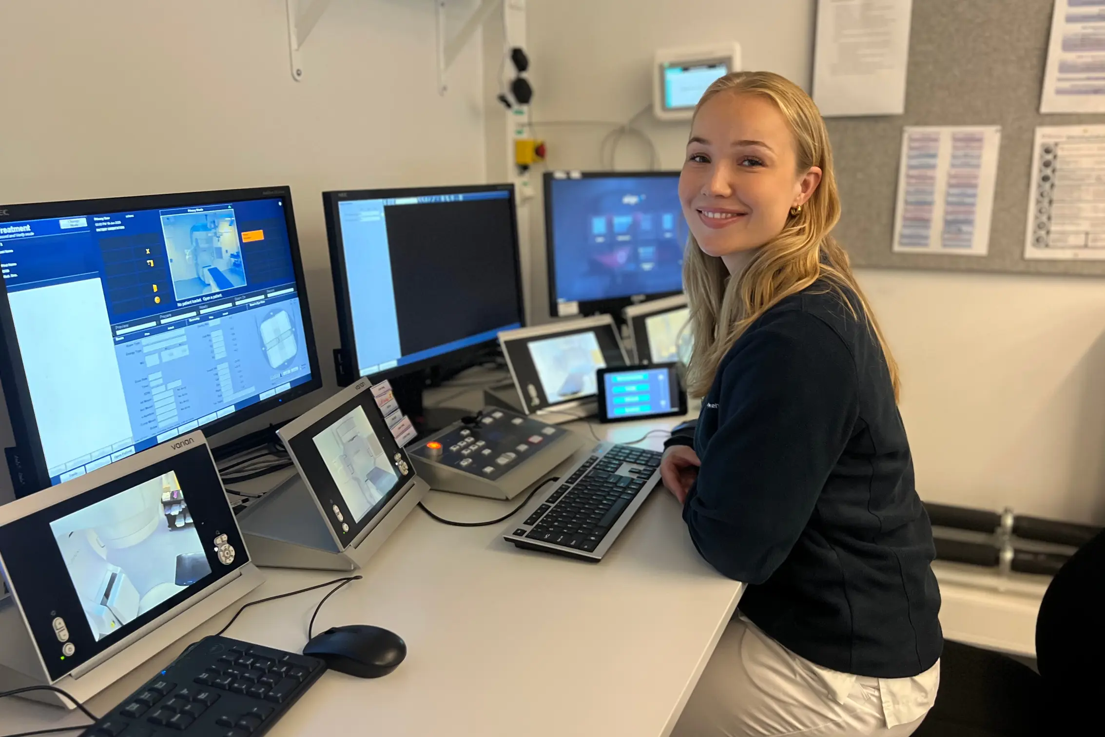 En person som står ved siden av et bord med flere datamaskiner