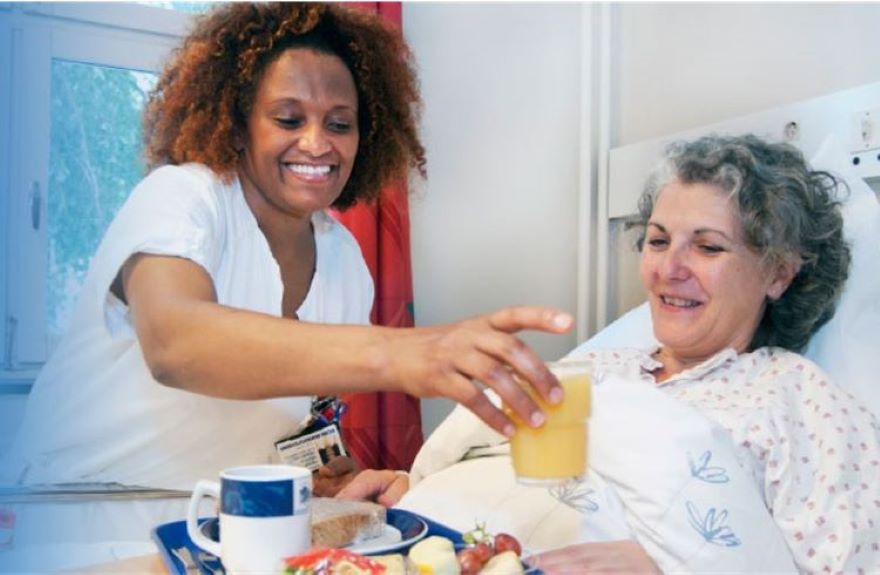 Et helsepersonell som hjelper en pasient i en sykeseng.