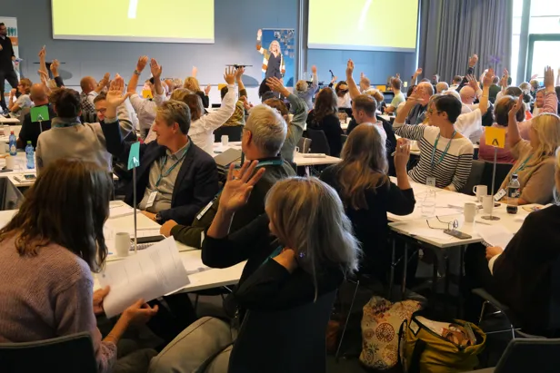 Foto av deltakere på TSB-lederkonferansen som rekker hånden i været