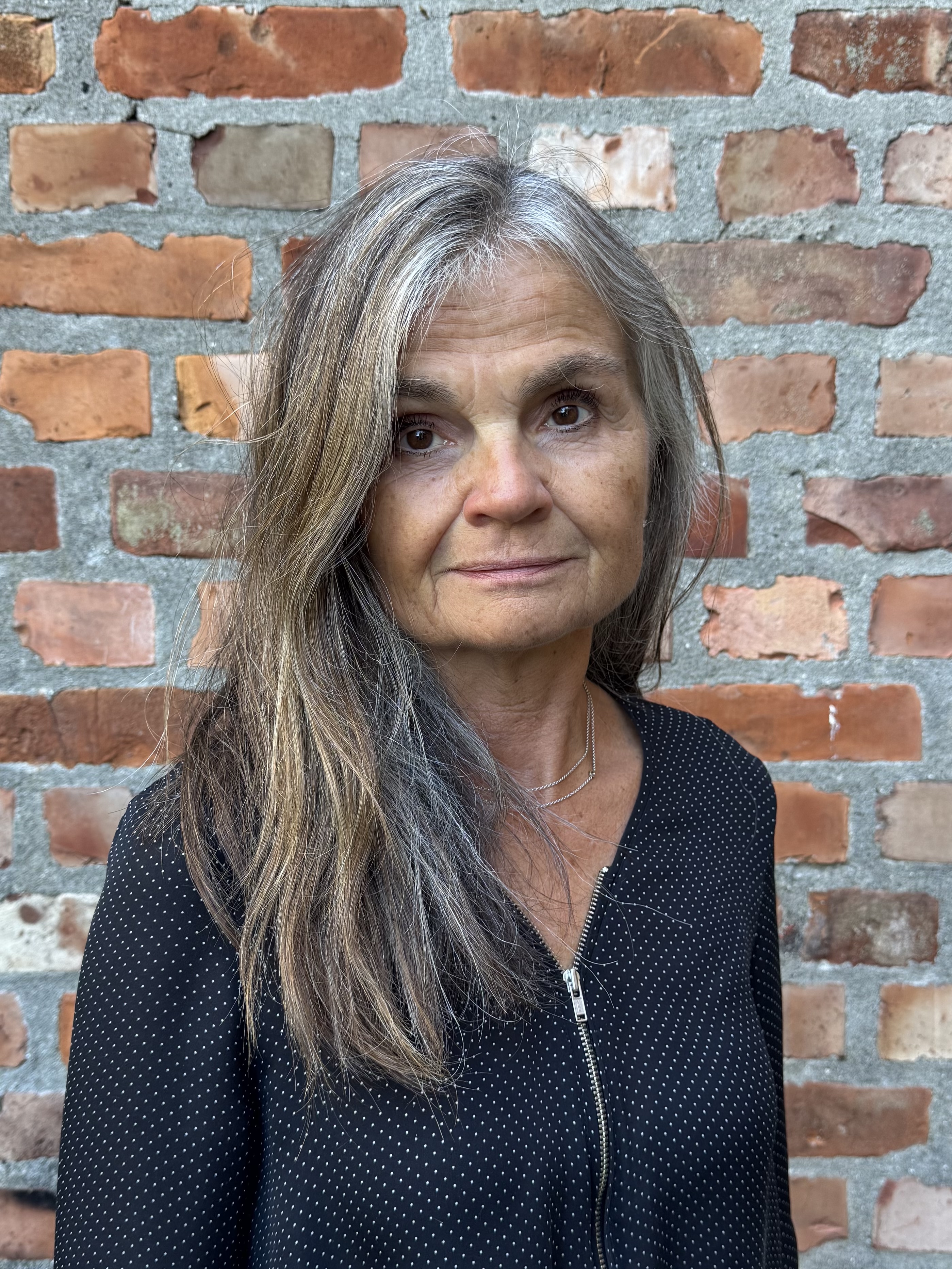 Kvinne foran en murvegg