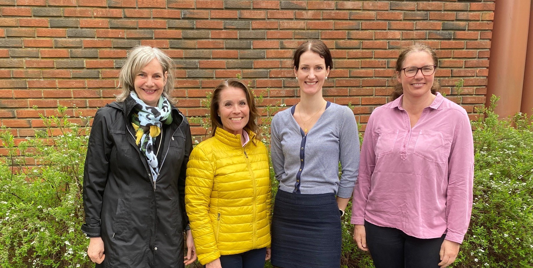 En gruppe kvinner som står foran en murvegg