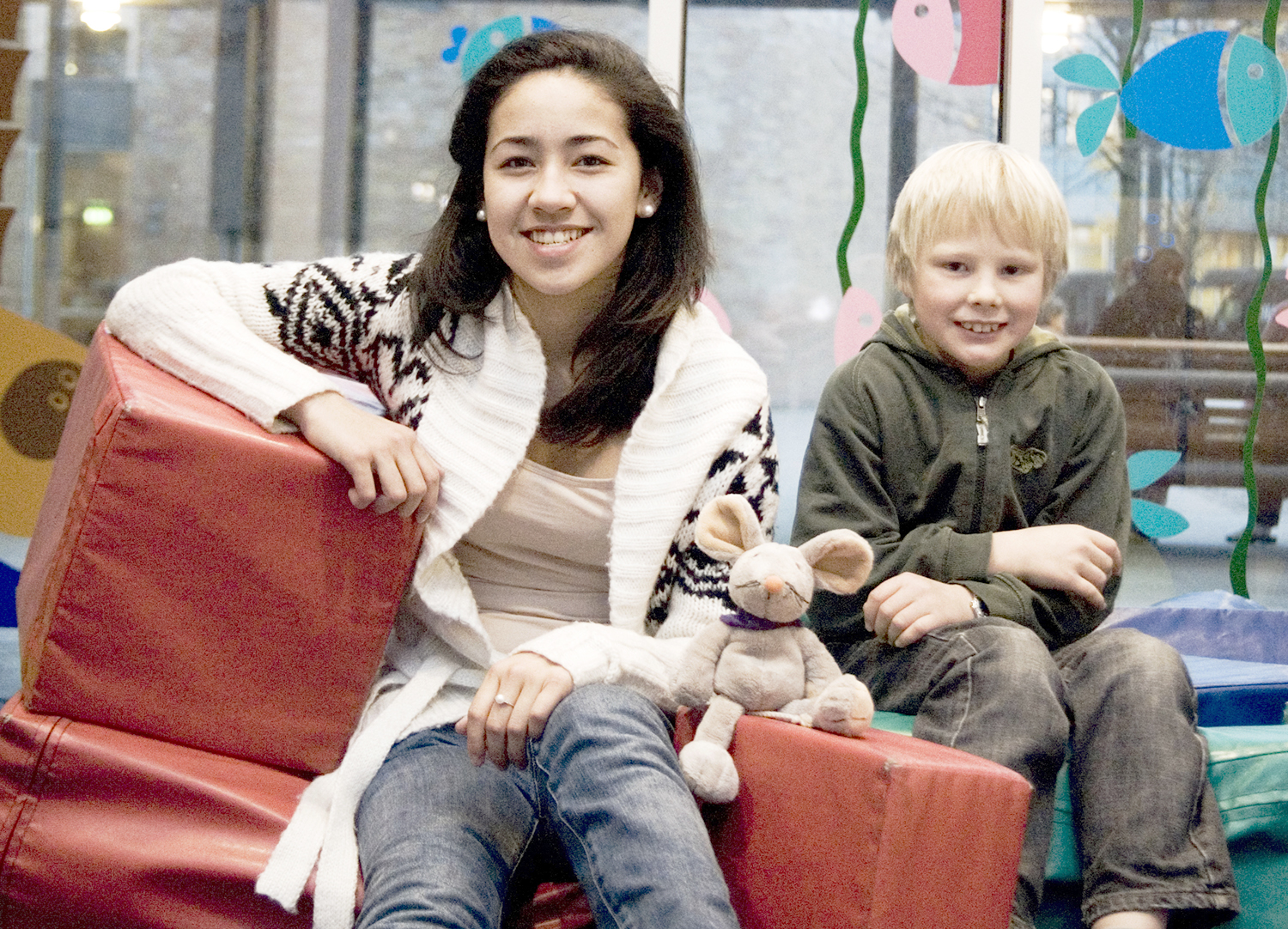 En person og et barn som sitter på en sofa med kosedyr