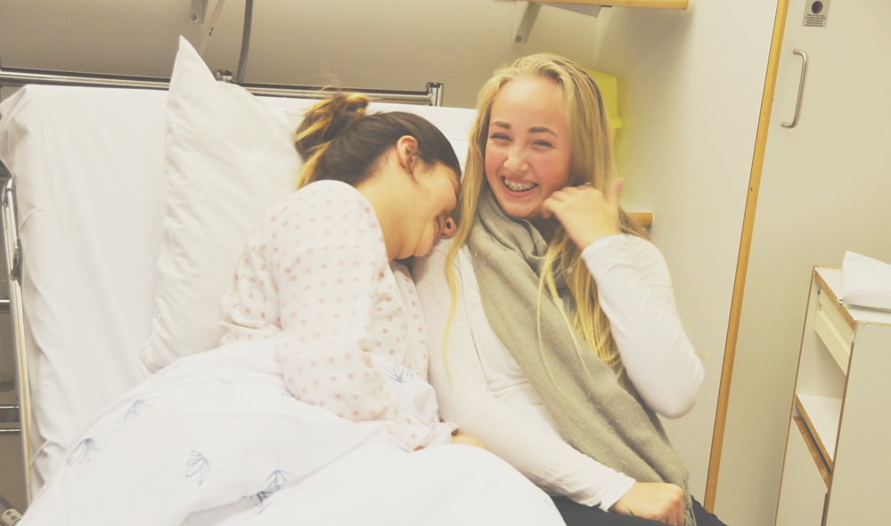 En person og et barn i en sykehusseng;