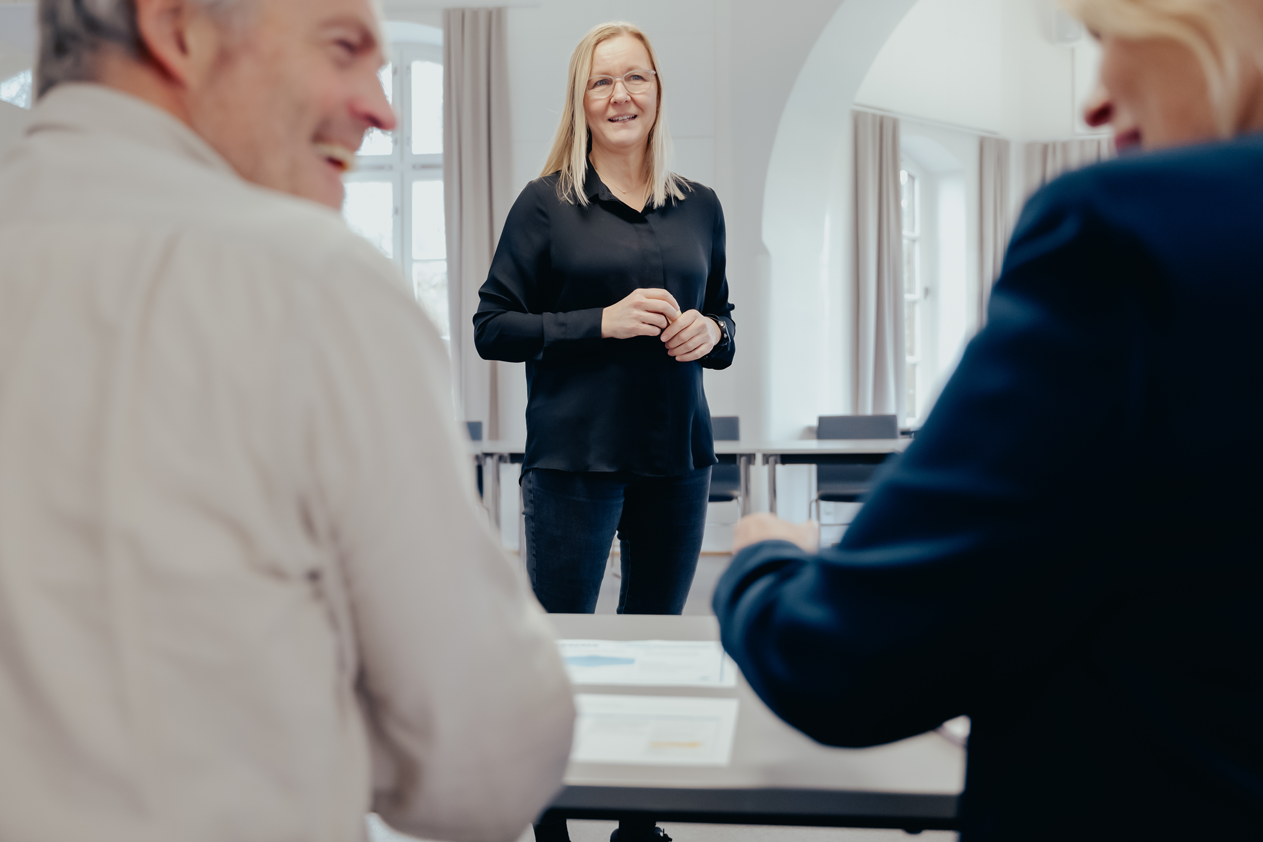 Foto av tre personer i hyggelig dialog på et møterom