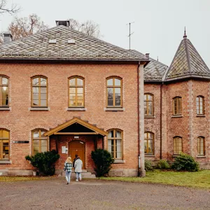 Tre mennesker går mot hoveddøra i Nasjonal kompetansetjeneste TSBs kontorlokale på Gaustad sykehus.