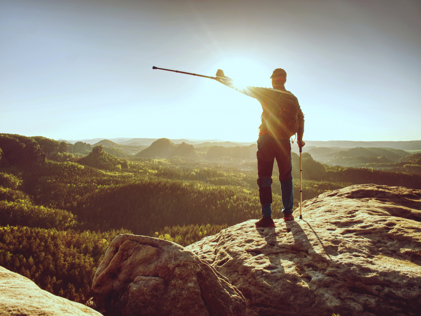 En mann som står på en stein med en pinne i hånden